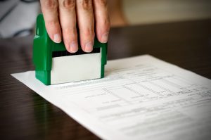 Male hand pressing rubber stamp on document